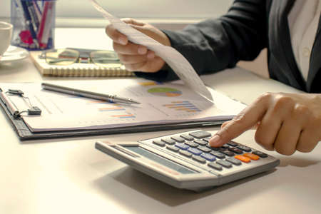 Business women who are using their fingers to press the calculator for calculating bills in the office.の写真素材