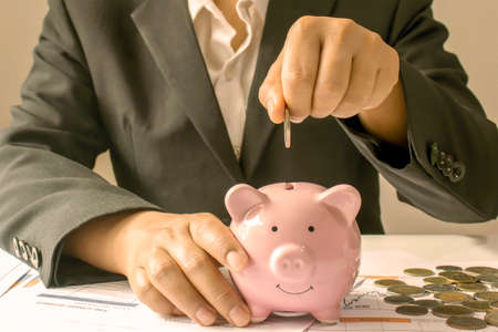 Business women who put coins in a piggy bank, the concept of saving money and saving money for the future.の写真素材