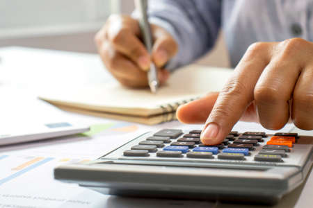 Close-up of women using calculators and note-taking, accounting reports, cost-calculation ideas, and saving money.の写真素材