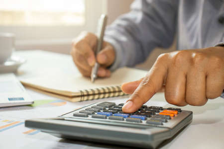Close-up of women using calculators and note-taking, accounting reports, cost-calculation ideas and saving money.の写真素材