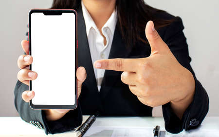 Mobile phone with a white screen for putting text and pictures in the hands of business women in a black dress.の写真素材