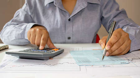 Close-up of a woman examining an accounting report and using a calculator for financial auditing...