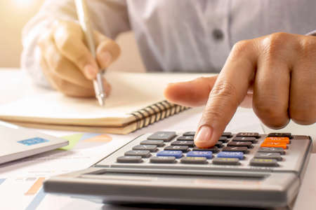 Close-up of women using calculators and note-taking, accounting reports, cost-calculation ideas and saving money.の写真素材