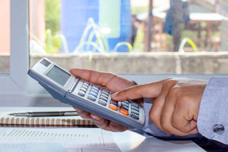 Close-up of a woman pressing the calculator to calculate expenses, calculation concepts, and saving money for the future.の写真素材