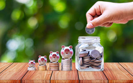 Hands are putting money in jars to save money.の写真素材