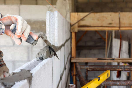 The hands of professional construction assistants lay bricks at the construction site. Labor concept.の写真素材