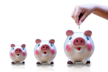 Hand put the coin into the piggy bank of different sizes isolated on white background.