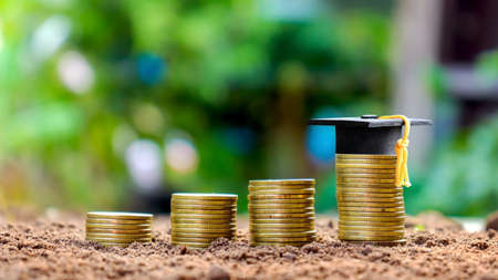 Graduation cap on a stack of medals background nature green blur concept education saving money