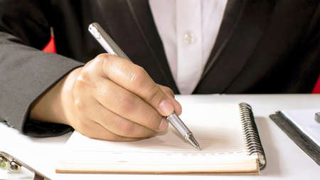 A woman who uses a pen to write wooden desk notebooks and memos.