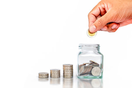 Hand holding coin put into money saving bottle on white background money saving idea to invest in the future.の写真素材