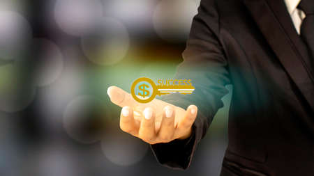 The road to success concept, key to success icon is in the hands of the businessman and the background is blurred.の写真素材