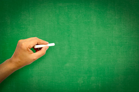 hand holding chalk writing on green chalk board good texture idea for text or background for copy space.の写真素材