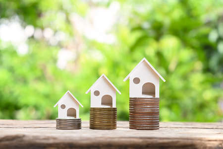 Model of a mock house on a pile of coins and blurred natural green background. Real Estate Investment Ideas Mortgage and home building interest ratesの写真素材