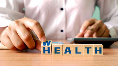 financial wealth concept Investing in life insurance and health. The young woman rolls the wooden dice with wealth and health.の写真素材
