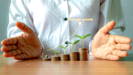 Tree growing on pile of money and growing graph, financial growth ideas and maximizing profit from business investment.の写真素材