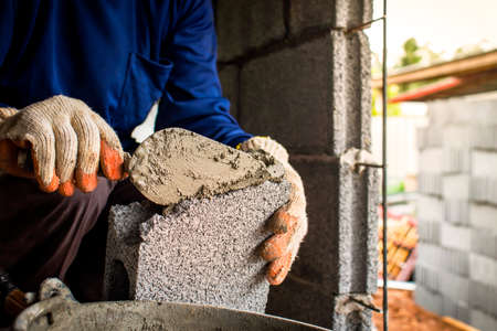 Close-up of a professional worker using a pan knife to build a brick wall with cement bricks and cement. Business ideas and the construction industryの写真素材