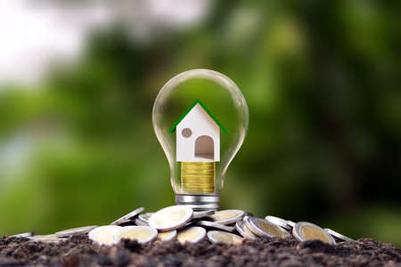 Model houses are on piles of coins in energy-saving lamps. energy saving concept Renewable energy and real estate investment loansの写真素材