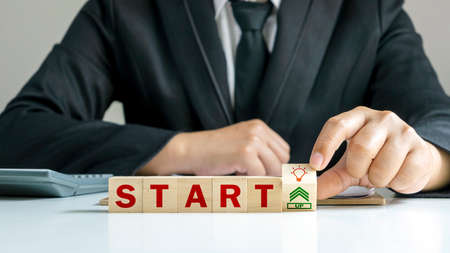 Businessman flipping wooden cube blocks with words Startup by hand, business start-up ideas and innovation and start-up technology.の写真素材