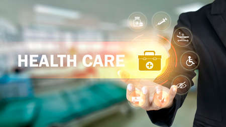 Businessman holding icons with medical symbols on blurry background, health insurance concept. Health care and health insurance businessの写真素材