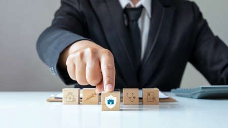 the medical icon on wooden cube block and male businessman chooses medical protection icon on wooden cube block Concept of planning for self and family health care.の写真素材