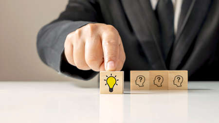 Businessman choosing light bulb icon, full of ideas and creativity on the wooden cube, financial planning ideas to achieve goals.の写真素材