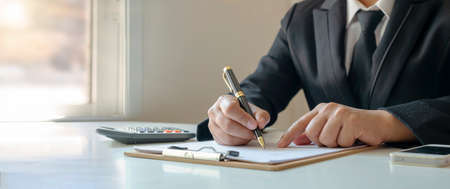 businessman taking notes and checking reports of financial documents to analyze financial data Work concepts, checking accounting documents, and signing contracts.の写真素材