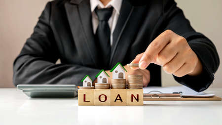 Model house on a pile of coins and businessman holding coins Real estate investment ideas and home loans, new home loans, low-interest rates on homes.の写真素材
