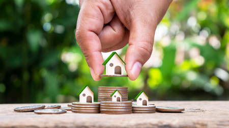 hand holding model house on a pile of coins real estate investment concept Mortgage and home building interest ratesの写真素材