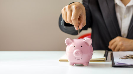 Place coins in the piggy bank to save money. Ideas for saving, investing, finances, and saving money for the future.の写真素材