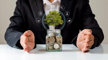 Tree growing on a pile of coins and investment icons with the concept of financial system development and economic growth.の写真素材