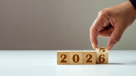 Hand changing wooden blocks from 2025 to 2026, representing the new year transition. Ideal for...