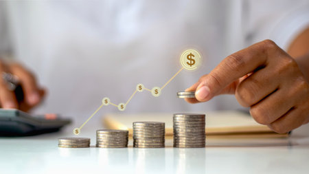 Businessman hand stacking coins with growing financial graph and dollar icons, concept of...