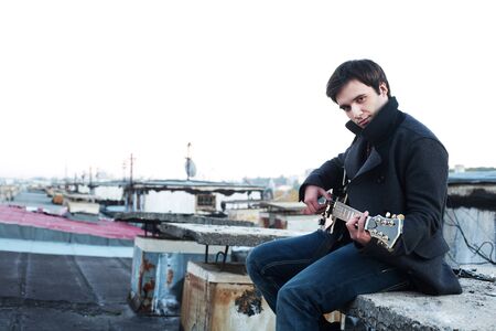 guy with a guitar on the roofの写真素材