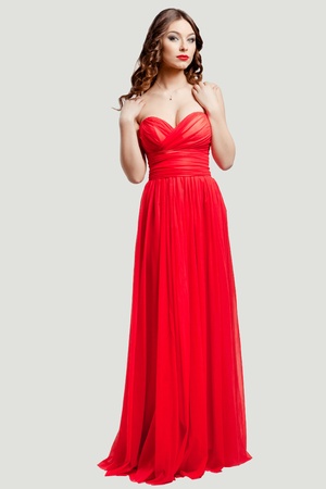 Beautiful female fashion model posing in red dress in studioの写真素材