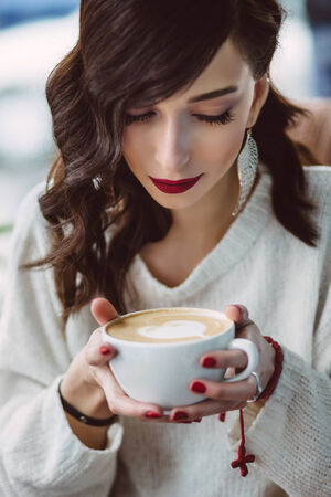 Young girl drinking coffee in a trendy cafeの写真素材