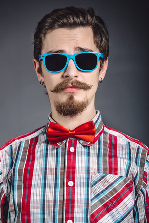 Man in plaid shirt and bow tie with glasses in the studioの写真素材