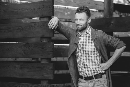 Black and white portrait of young fashionable man against wooden fenceの写真素材