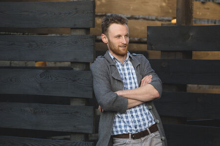Portrait of young fashionable man against wooden fenceの写真素材