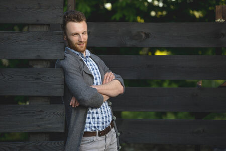 Portrait of young fashionable man against wooden fenceの写真素材