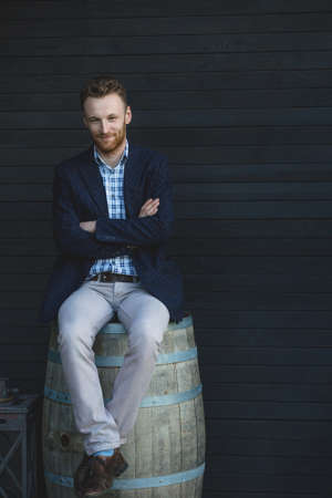 Man in a jacket sitting on a barrelの写真素材