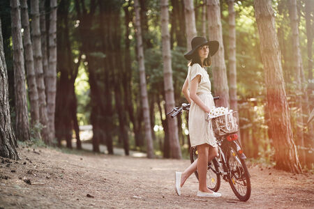 Girl on a bicycle in coniferous forestの写真素材