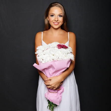 Young woman with bouquet of flowers over black backgroundの写真素材