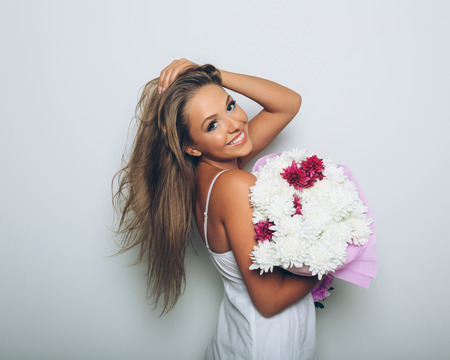 Young woman with bouquet of flowers over white backgroundの写真素材