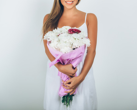 Young woman with bouquet of flowers over white background. Close upの写真素材