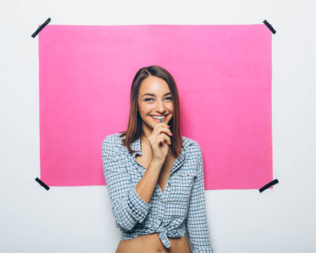 Happy young woman with lollipop on pink backgroundの写真素材