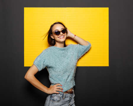 Smiling girl in glasses on yellow backgroundの写真素材