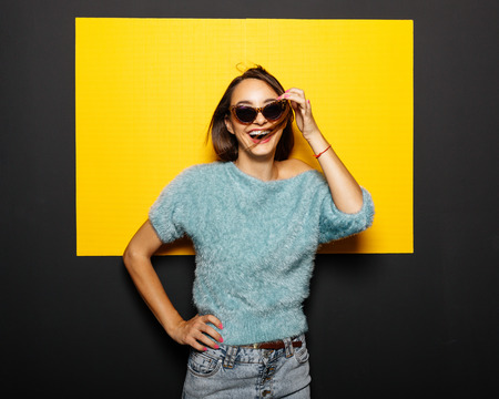 Smiling girl in glasses on yellow backgroundの写真素材