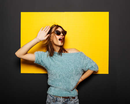 Smiling girl in glasses on yellow backgroundの写真素材