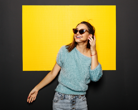 Smiling girl in glasses on yellow backgroundの写真素材