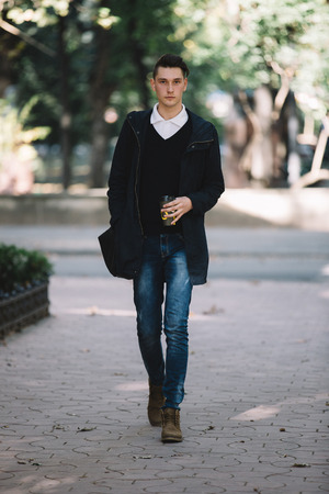 Stylish hipster model walking and holding coffee and brief caseの写真素材